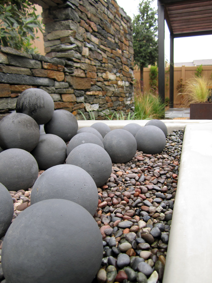 Immagine di un giardino minimal esposto in pieno sole di medie dimensioni e dietro casa con un focolare e pavimentazioni in pietra naturale