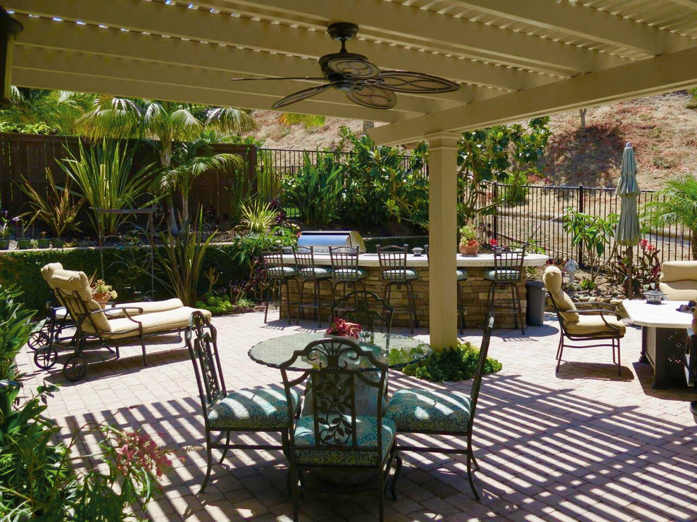 Design ideas for a mid-sized mediterranean partial sun backyard brick landscaping in San Diego with a fire pit.