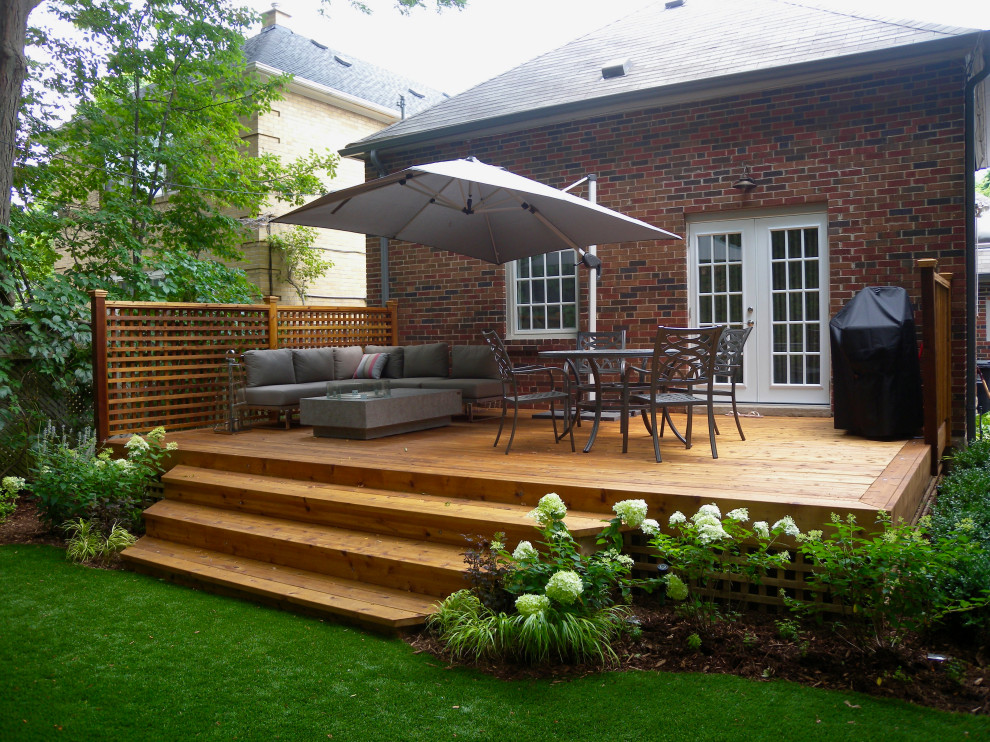 Cette image montre un petit jardin arrière design l'été avec une exposition partiellement ombragée et une terrasse en bois.