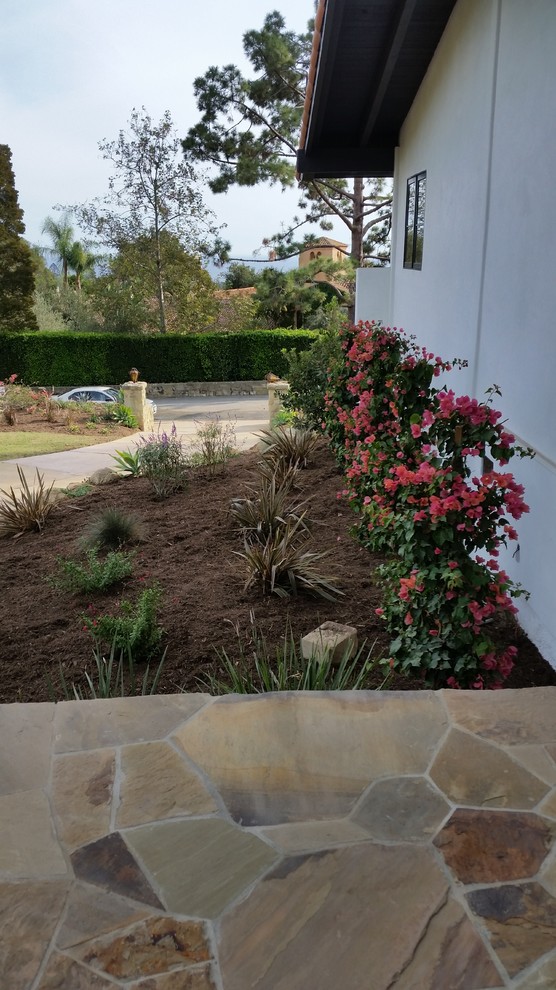 Diseño de camino de jardín de secano mediterráneo grande en primavera en patio delantero con exposición parcial al sol y adoquines de piedra natural