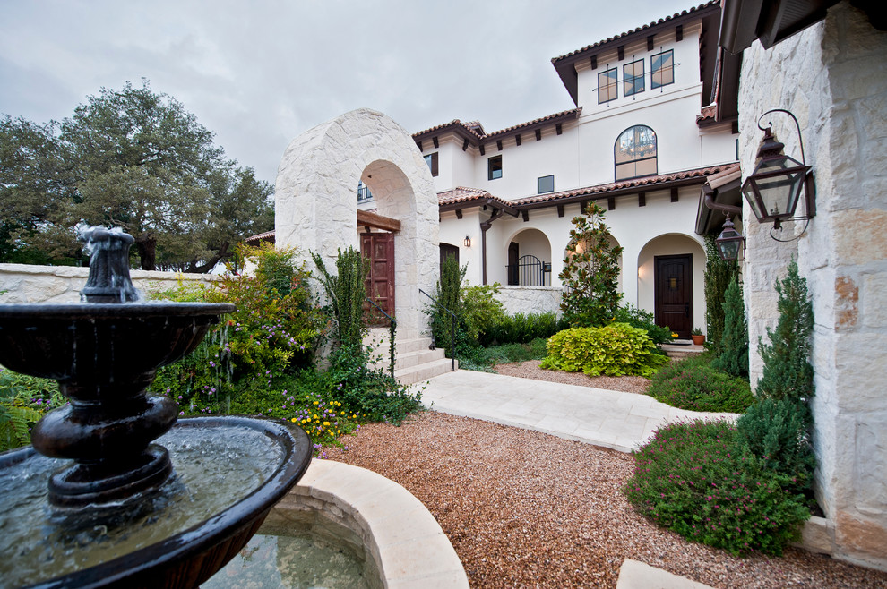 This is an example of a large mediterranean full sun backyard stone landscaping in Austin.