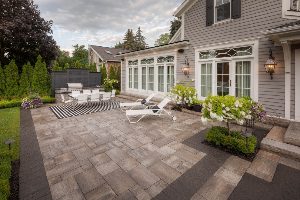 This is an example of a large contemporary back patio in Toronto with natural stone paving.