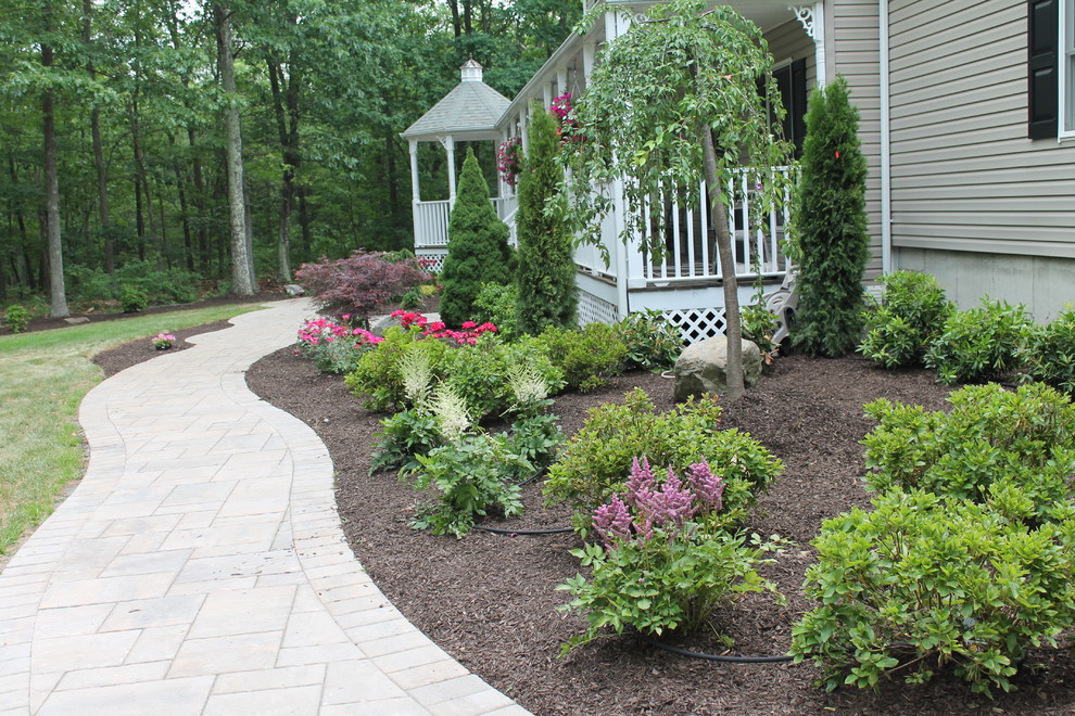 This is an example of a large traditional full sun front yard stone formal garden in New York with a fire pit.