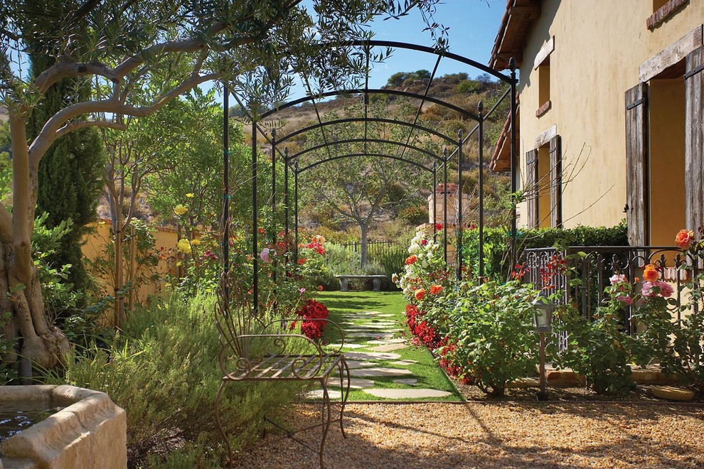 Idéer för en mellanstor medelhavsstil formell trädgård i delvis sol längs med huset på våren, med en trädgårdsgång och naturstensplattor