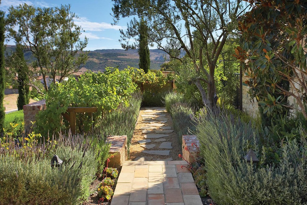 Стильный дизайн: весенний участок и сад на переднем дворе в средиземноморском стиле с покрытием из каменной брусчатки, садовой дорожкой или калиткой и полуденной тенью - последний тренд