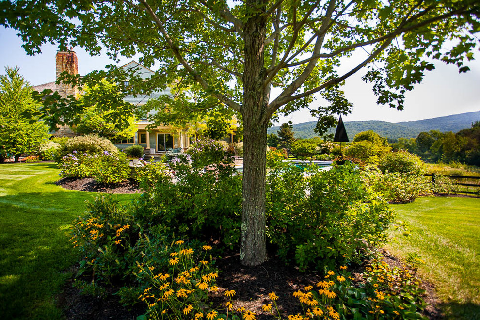 На фото: огромный летний участок и сад на заднем дворе в стиле кантри с полуденной тенью и мульчированием