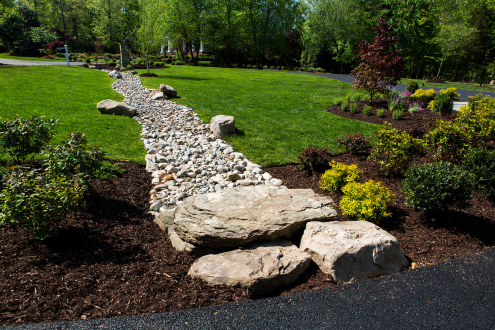 This is an example of an expansive rustic front full sun garden in DC Metro with natural stone paving.