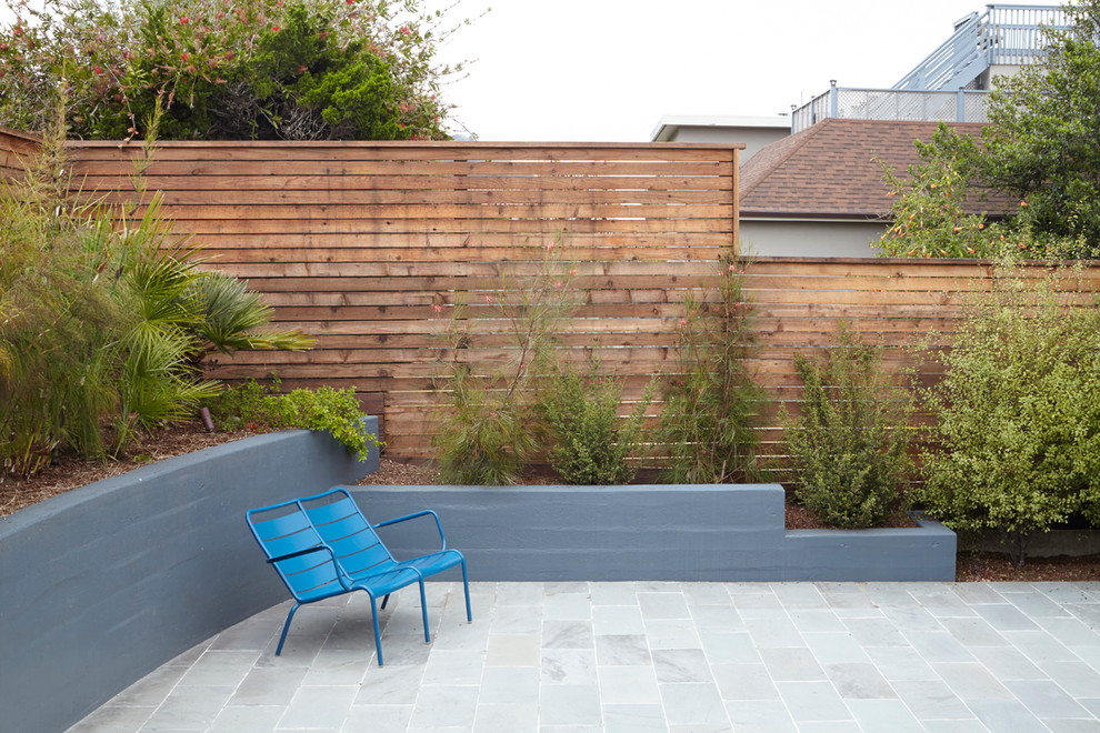 Imagen de jardín minimalista de tamaño medio en patio trasero con exposición total al sol y adoquines de piedra natural