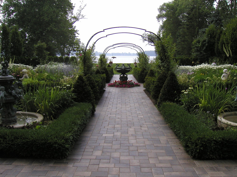 Foto de jardín tradicional de tamaño medio en patio trasero con jardín francés y adoquines de ladrillo