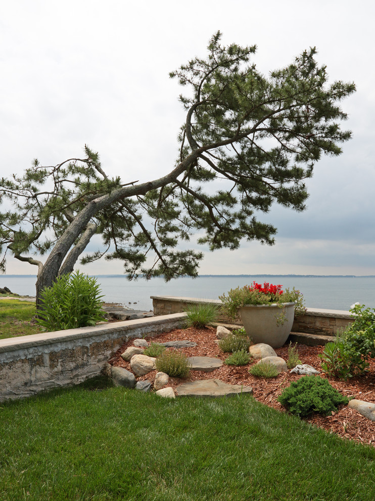 Idee per un grande giardino formale costiero esposto in pieno sole dietro casa in estate con un muro di contenimento e pavimentazioni in pietra naturale