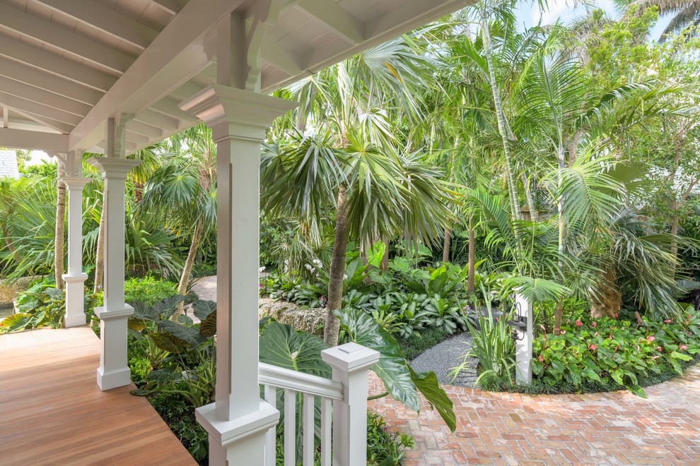 Inspiration för en mellanstor tropisk trädgård i delvis sol framför huset, med marksten i tegel