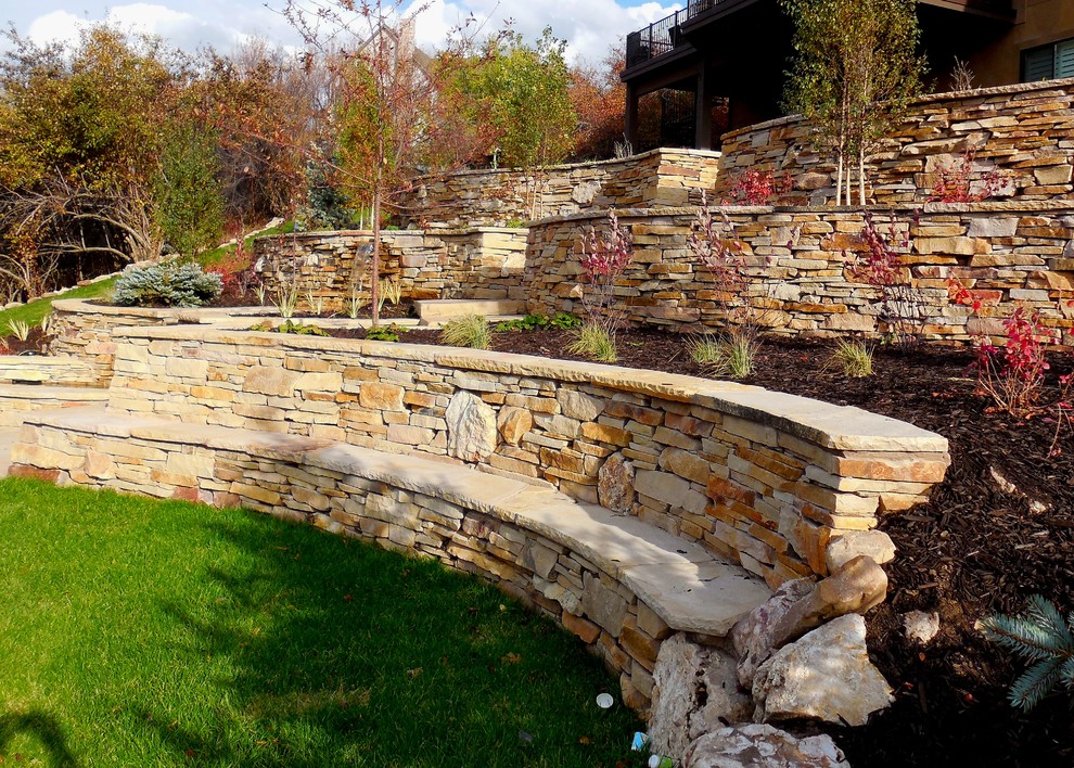 Photo of a medium sized classic sloped partial sun garden in Salt Lake City with natural stone paving and a retaining wall.
