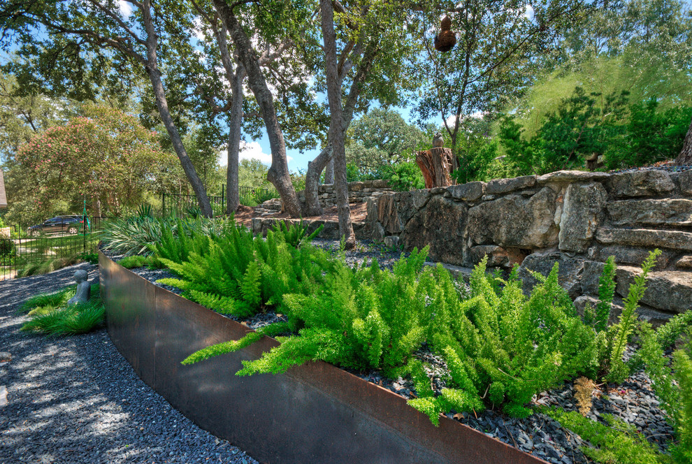 Стильный дизайн: большой тенистый, весенний засухоустойчивый сад на заднем дворе в стиле модернизм с подпорной стенкой и покрытием из гравия - последний тренд