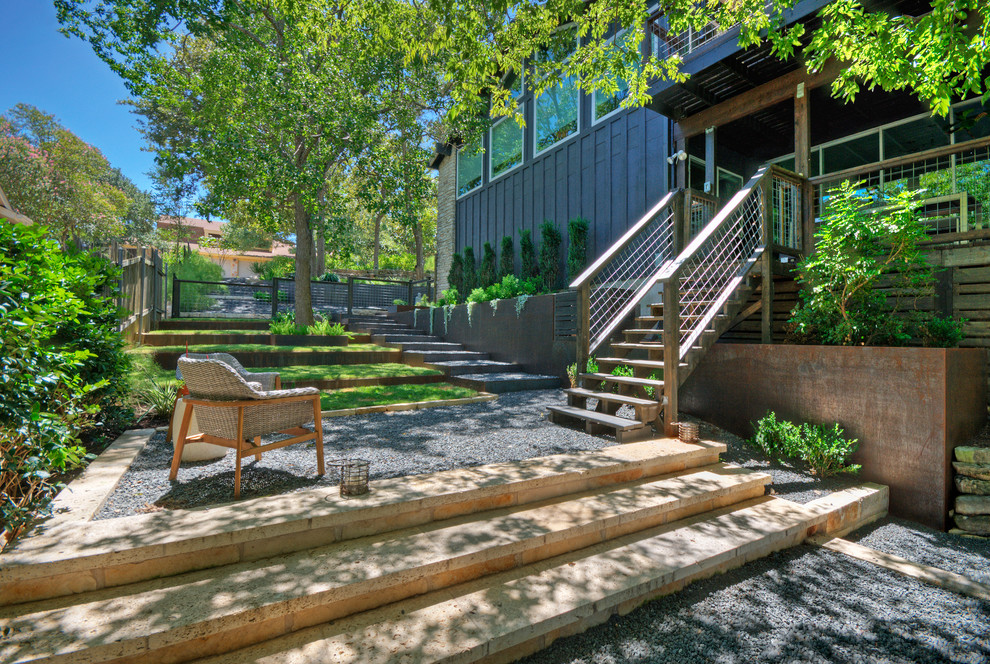 Diseño de jardín de secano moderno grande en primavera en patio trasero con muro de contención, exposición reducida al sol y gravilla