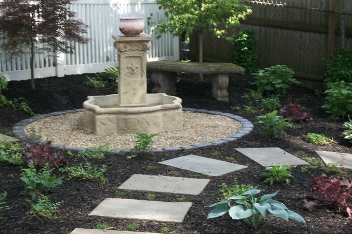 Immagine di un giardino chic di medie dimensioni e dietro casa con fontane e pacciame