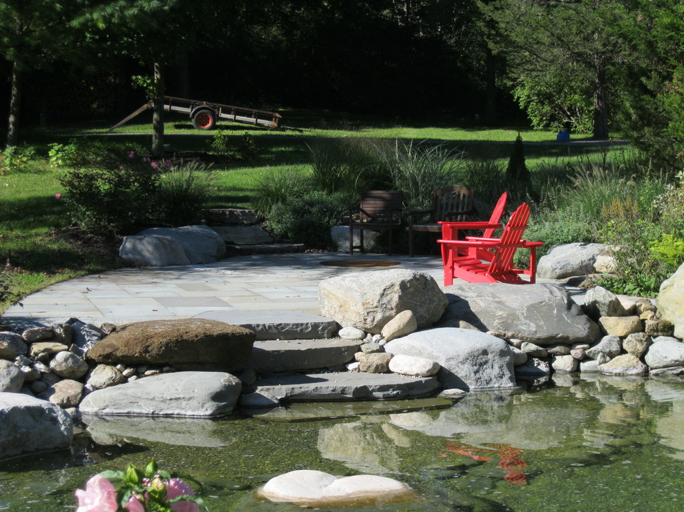 Photo of a mid-sized traditional partial sun backyard stone pond in Burlington.
