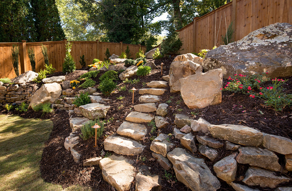Photo of a large rustic partial sun backyard stone retaining wall landscape in Atlanta.