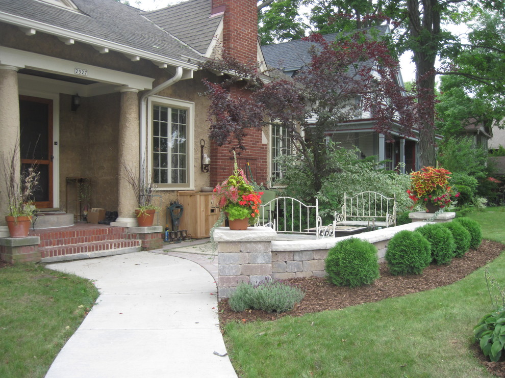 Exempel på en mellanstor klassisk trädgård framför huset, med naturstensplattor