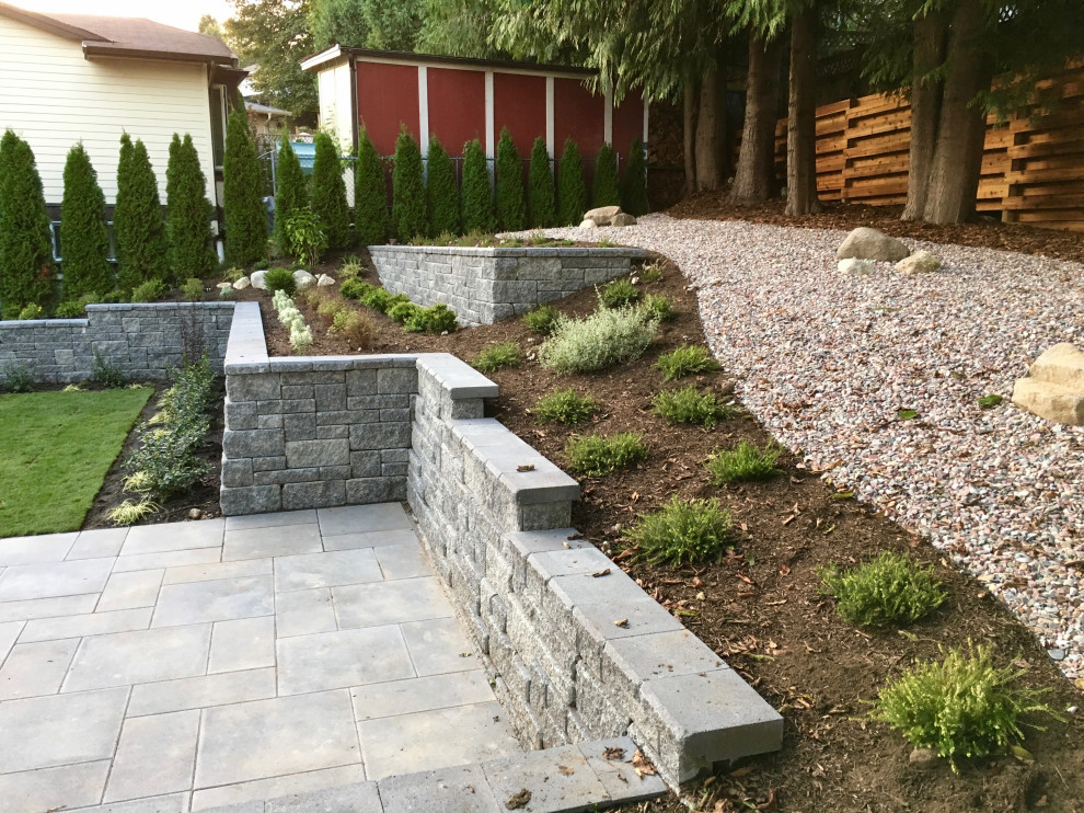 This is an example of a mid-sized modern partial sun hillside concrete paver raised garden bed in Vancouver.