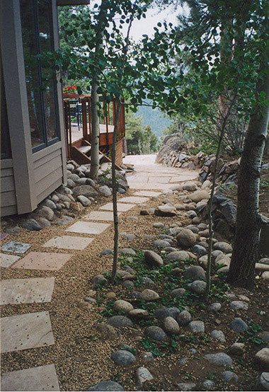 Cette image montre un grand jardin latéral chalet au printemps avec une exposition ombragée et des pavés en pierre naturelle.