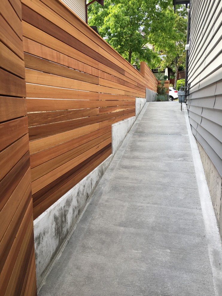 This is an example of a medium sized modern side garden in Vancouver with a retaining wall.