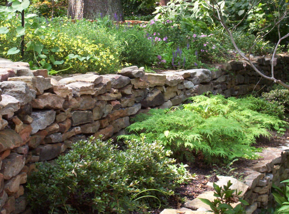 Esempio di un giardino classico esposto a mezz'ombra di medie dimensioni e dietro casa con un muro di contenimento e pavimentazioni in pietra naturale