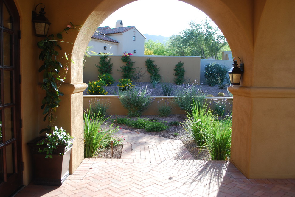 Inspiration for a large mediterranean side yard brick retaining wall landscape in Phoenix for spring.