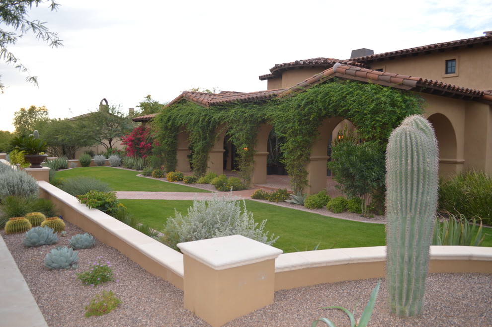 This is an example of a large mediterranean full sun front yard brick retaining wall landscape in Phoenix for spring.