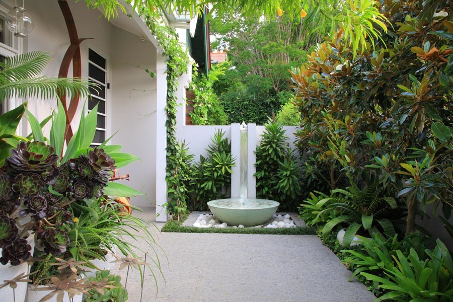 Ejemplo de jardín minimalista con fuente, exposición parcial al sol y adoquines de hormigón