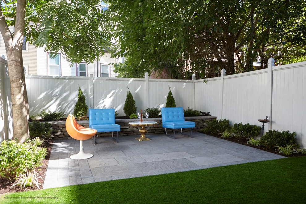 This is an example of a small mid-century modern shade backyard concrete paver retaining wall landscape in New York for winter.