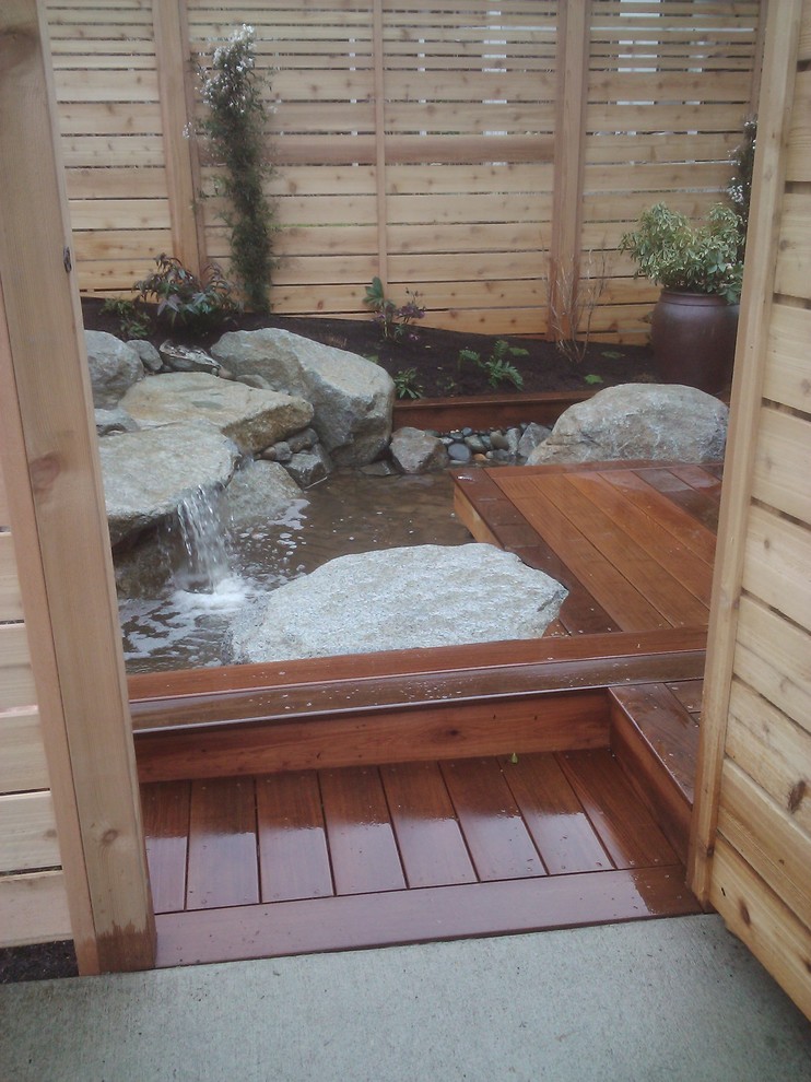 Inspiration for a large modern full sun backyard pond in Seattle with decking.