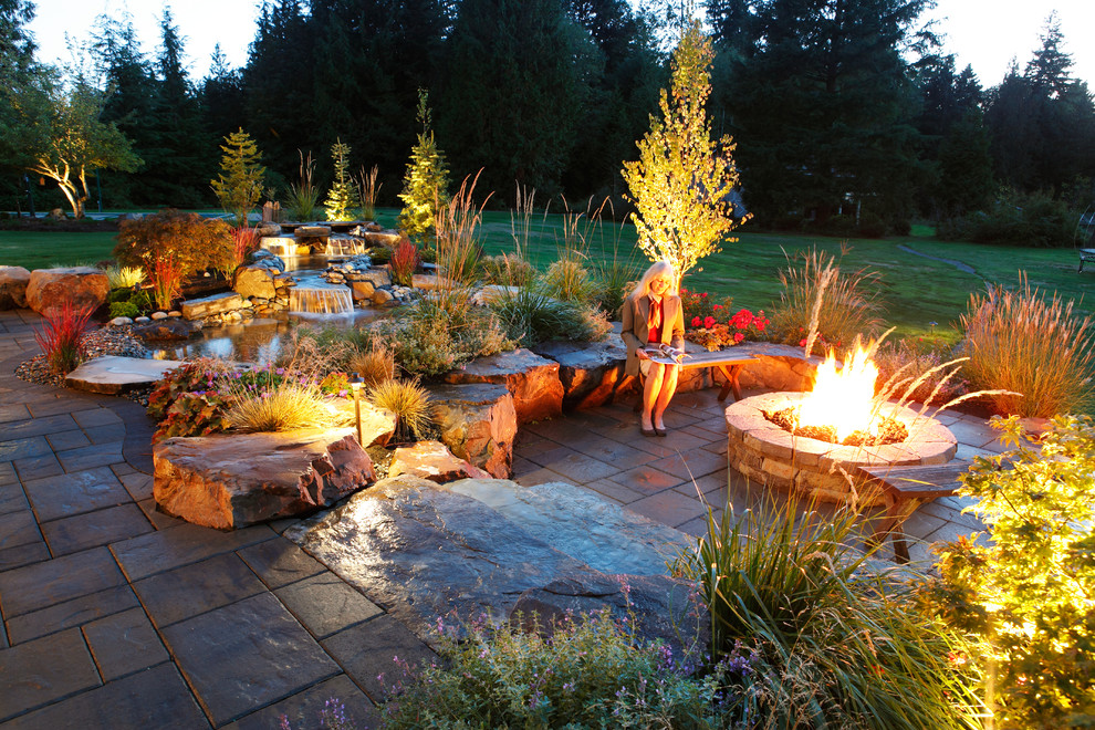 Diseño de jardín de estilo americano grande en patio trasero con brasero, exposición total al sol y adoquines de piedra natural