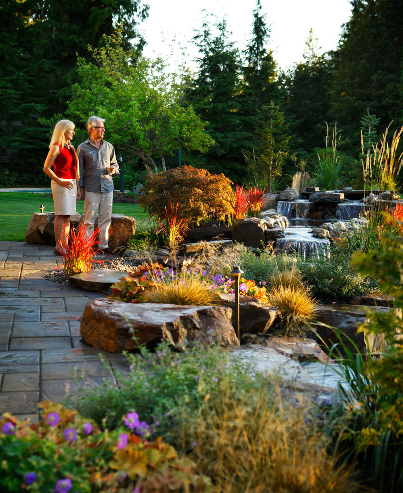 Idee per un grande giardino formale stile americano esposto in pieno sole dietro casa con fontane e pavimentazioni in pietra naturale