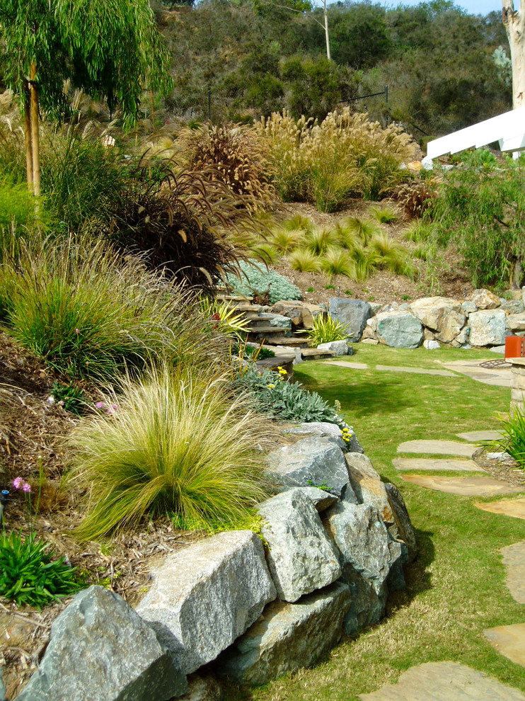 Diseño de jardín de estilo americano de tamaño medio en patio trasero con muro de contención y exposición total al sol