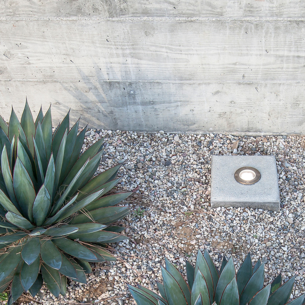 Ispirazione per un giardino design esposto in pieno sole dietro casa con un muro di contenimento e ghiaia