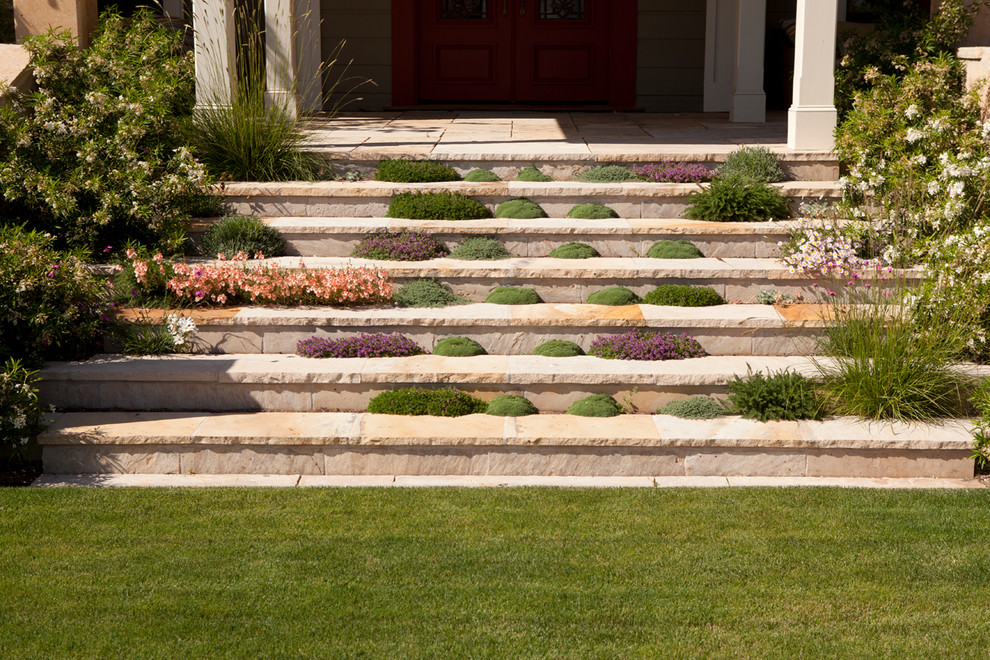 Esempio di un giardino tradizionale con pavimentazioni in pietra naturale e scale