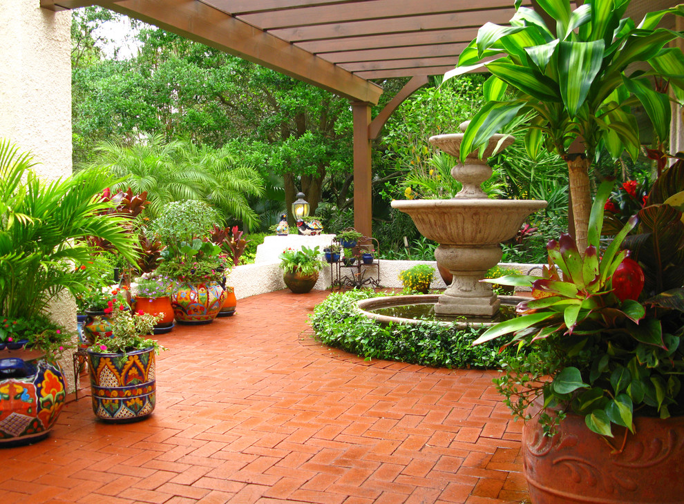 Photo of a mediterranean garden in Tampa with a water feature and brick paving.