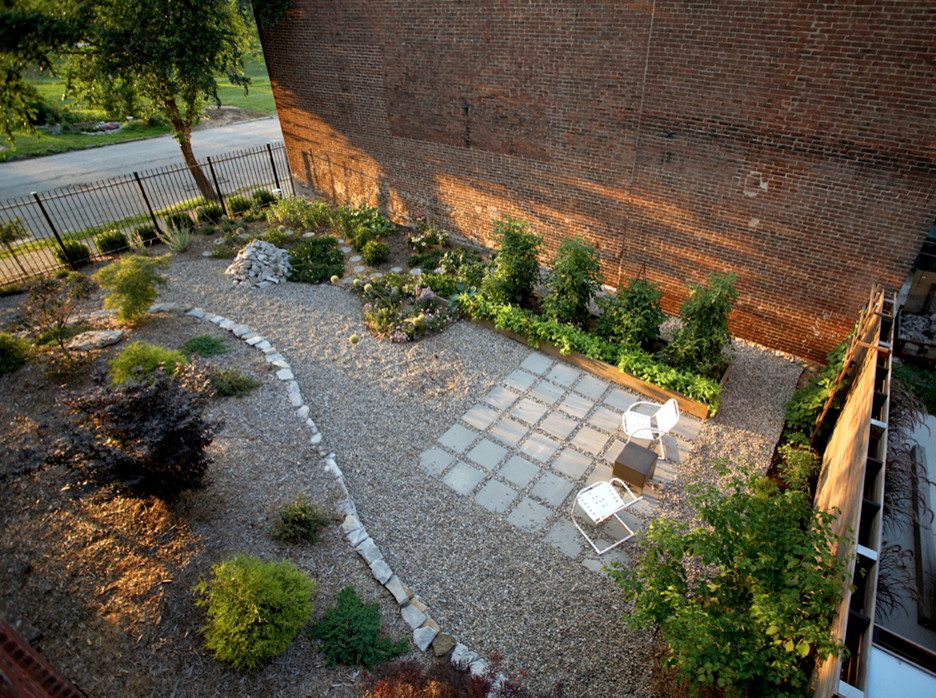Ejemplo de jardín industrial en primavera en patio lateral con muro de contención, exposición parcial al sol y adoquines de hormigón