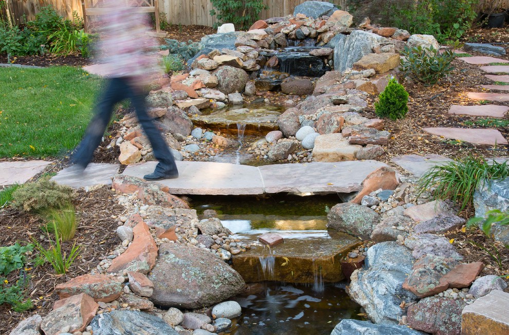 Halbschattiger Uriger Garten im Sommer, hinter dem Haus mit Wasserspiel und Natursteinplatten in Denver