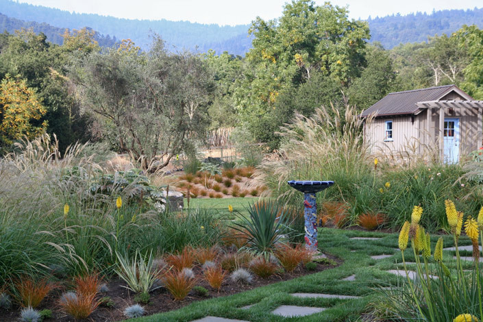 Immagine di un ampio giardino mediterraneo nel cortile laterale con un ingresso o sentiero e pavimentazioni in pietra naturale