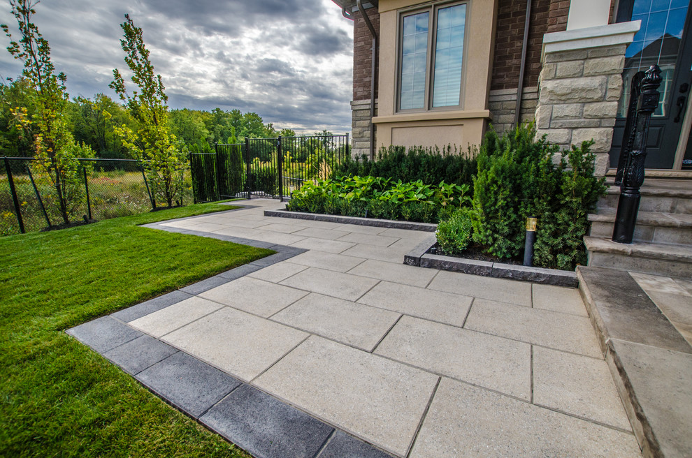 Design ideas for a large contemporary front driveway fully shaded garden for summer in Toronto with a garden path and natural stone paving.