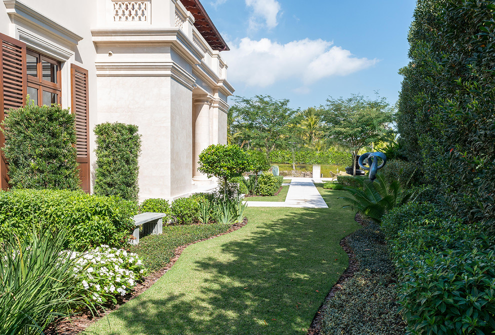 На фото: большой регулярный сад на заднем дворе в средиземноморском стиле с полуденной тенью и мощением тротуарной плиткой