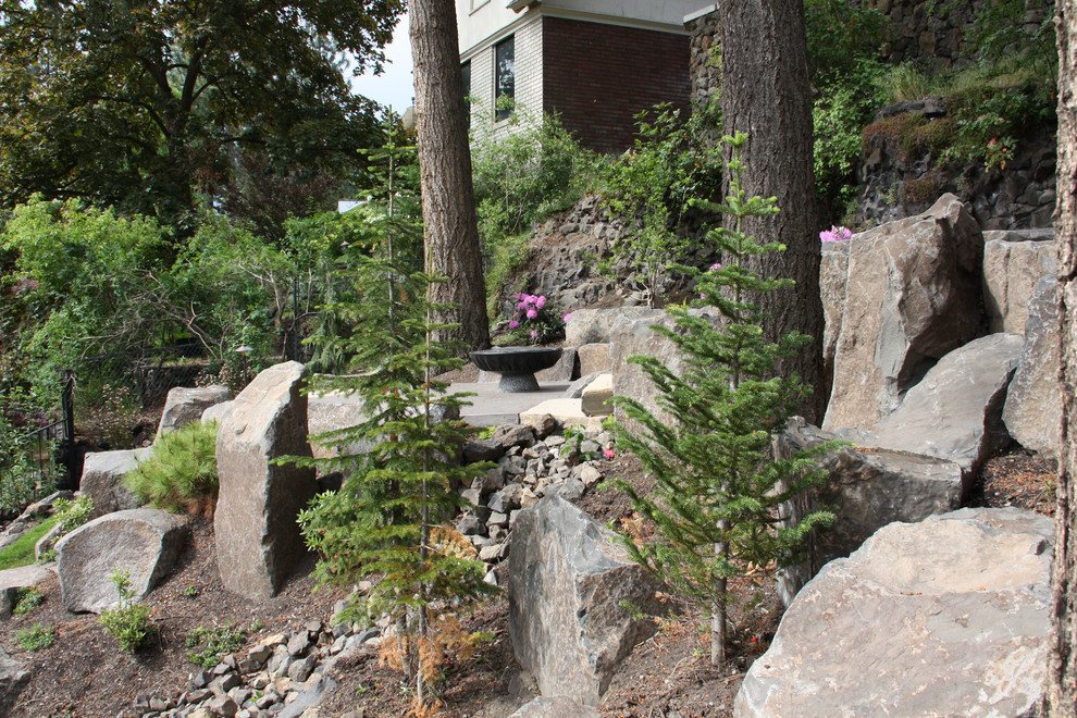 Exemple d'un grand jardin craftsman avec un mur de soutènement, une exposition partiellement ombragée, une pente, une colline ou un talus et un paillis.