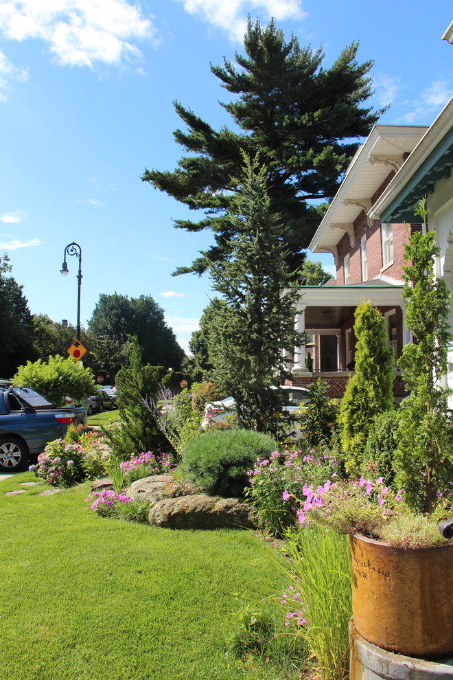 Foto di un piccolo giardino formale vittoriano esposto in pieno sole davanti casa in estate con un ingresso o sentiero e pavimentazioni in pietra naturale