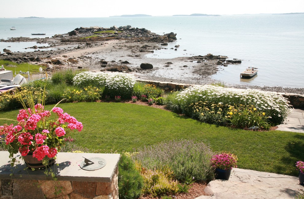Foto di un grande giardino formale costiero esposto in pieno sole dietro casa in estate