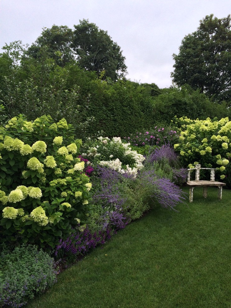 Aménagement d'un grand jardin arrière classique l'été avec une exposition partiellement ombragée.