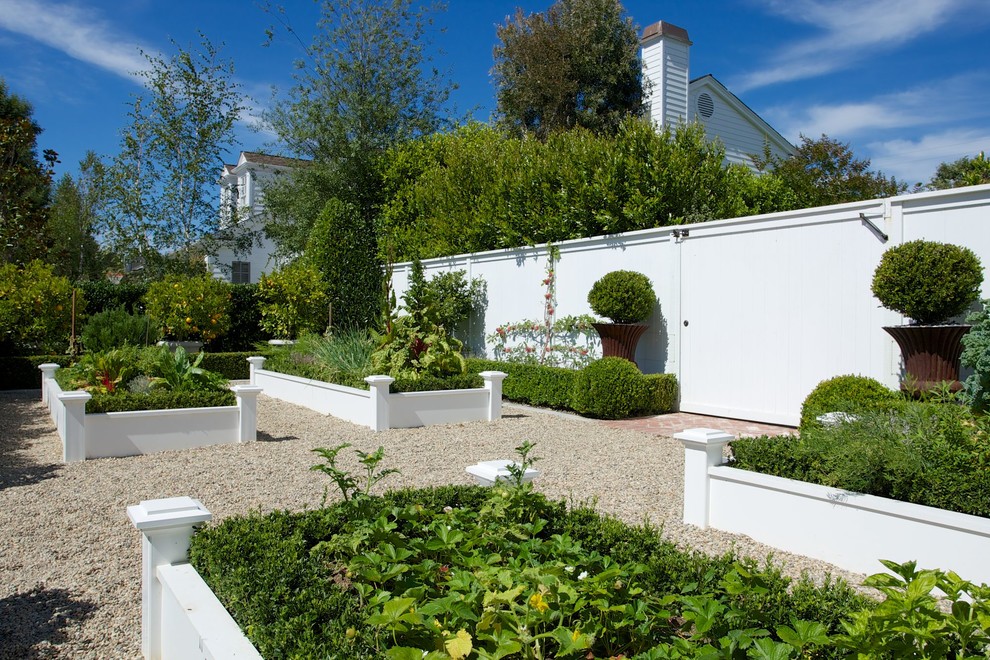 Diseño de jardín clásico en patio trasero con exposición total al sol, gravilla y macetero elevado