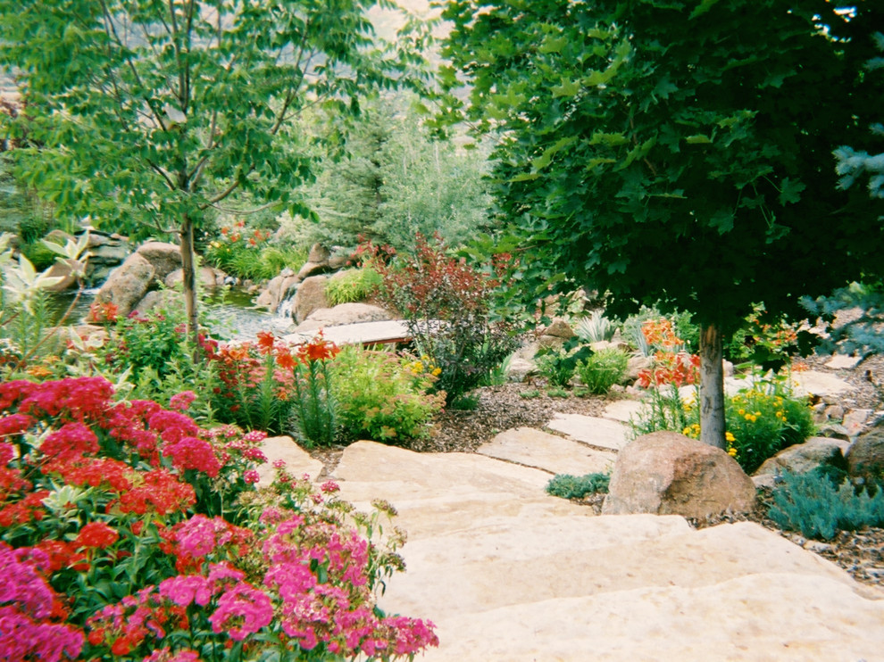 Ejemplo de jardín rural grande en patio trasero con fuente, exposición total al sol y adoquines de piedra natural