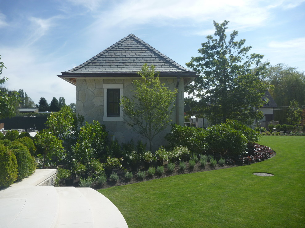 Diseño de jardín tradicional grande en patio lateral con jardín francés y exposición total al sol