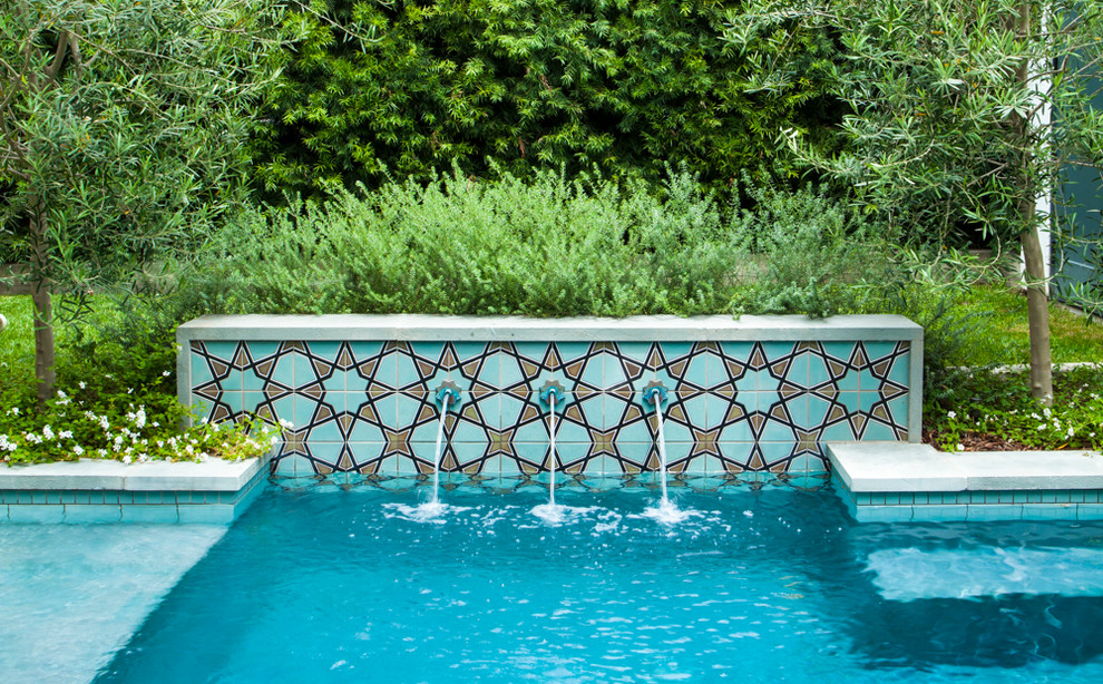 Ejemplo de piscina mediterránea pequeña en patio trasero con adoquines de piedra natural